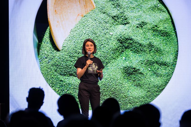 Woman on stage delivering presentation in front of an audience