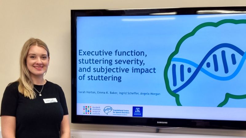 Sarah Horton, a white woman with blonde hair, gives a presentation titled 'Executive function, stuttering severity, and subjective impact of stuttering;