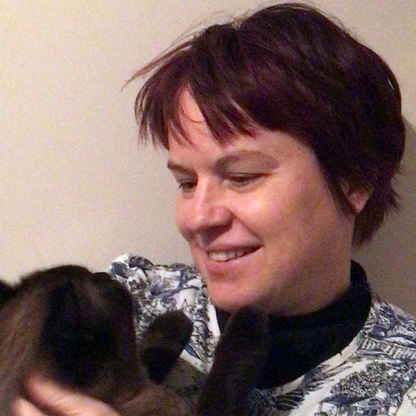 Helena Roennfeldt, a white woman with dark red hair, looks lovingly at a cat held in her arms