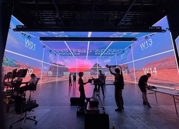 This image captures a virtual production shoot for Killjoy at Nant Studios in Melbourne (on the lands of the Wurundjeri Woi Wurrung people of the Kulin Nation). A real film set is embedded within an Unreal Engine–designed desert environment, displayed across a large-scale LED volume.