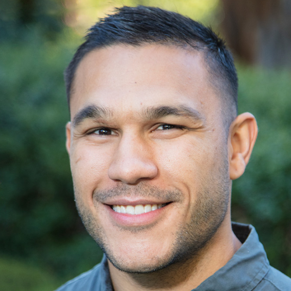 Josh Cubillo is a brown-skinned man with short-cropped black hair and a bright smile