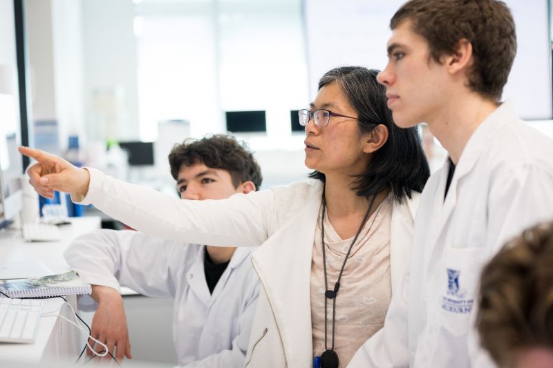 A senior scientist in a lab talking to younger scientists