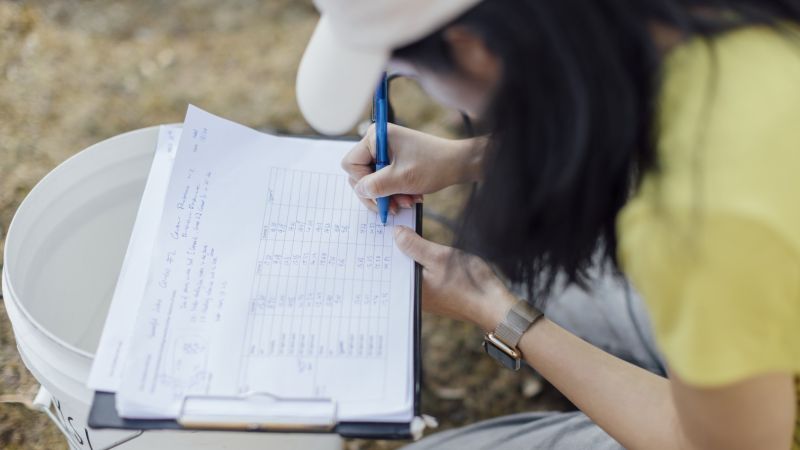 A researcher writing notes in the field