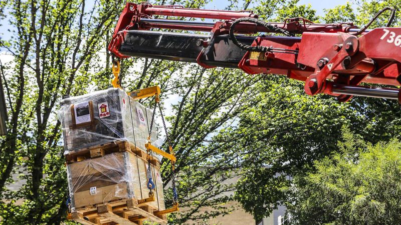 Red crane lifting a large box of a truck