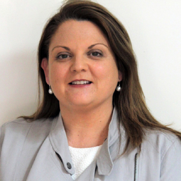 Katie Lamb is a light-skinned woman in professional attire with dark brown, long hair
