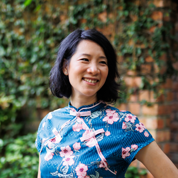 Elaine Pratley, an Asian woman with short black hair, smiles wearing a bright blue dress