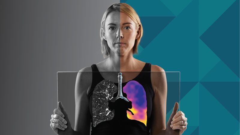 A woman holding a clear piece of glass in front of her chest, with a rendering of her lungs shown on the glass