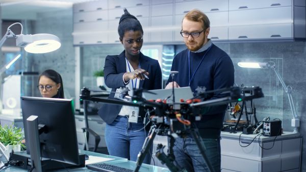 Two people in a laboratory examining a drone