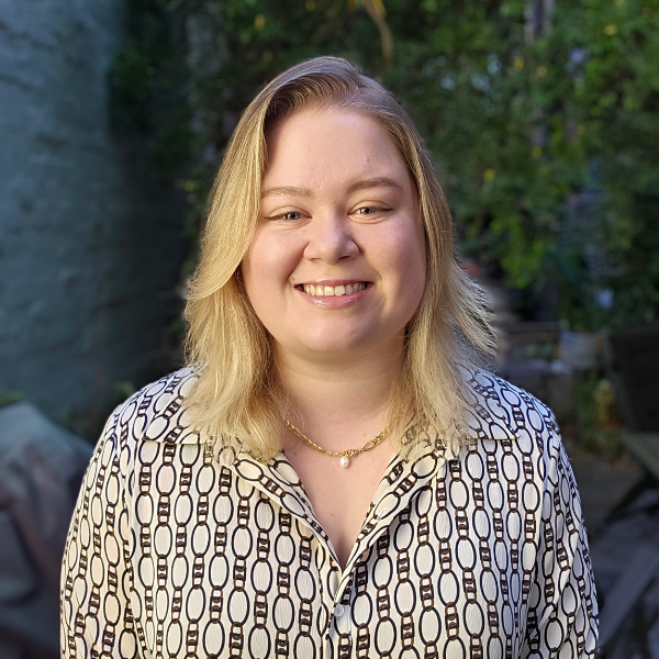 Julia Hall, a white woman with blonde hair and a neat black and white blouse, smiles brightly