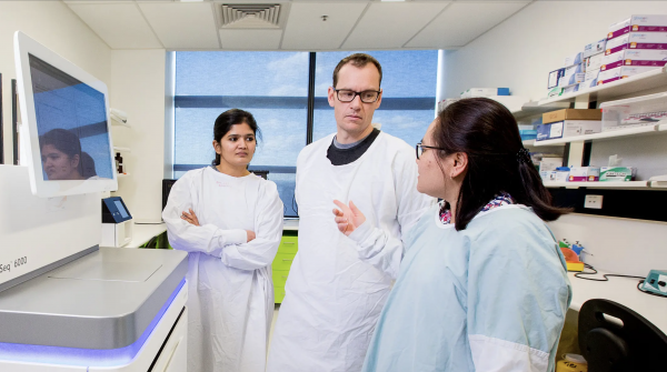 Three scientists in laboratory wearing lab coats in conversation