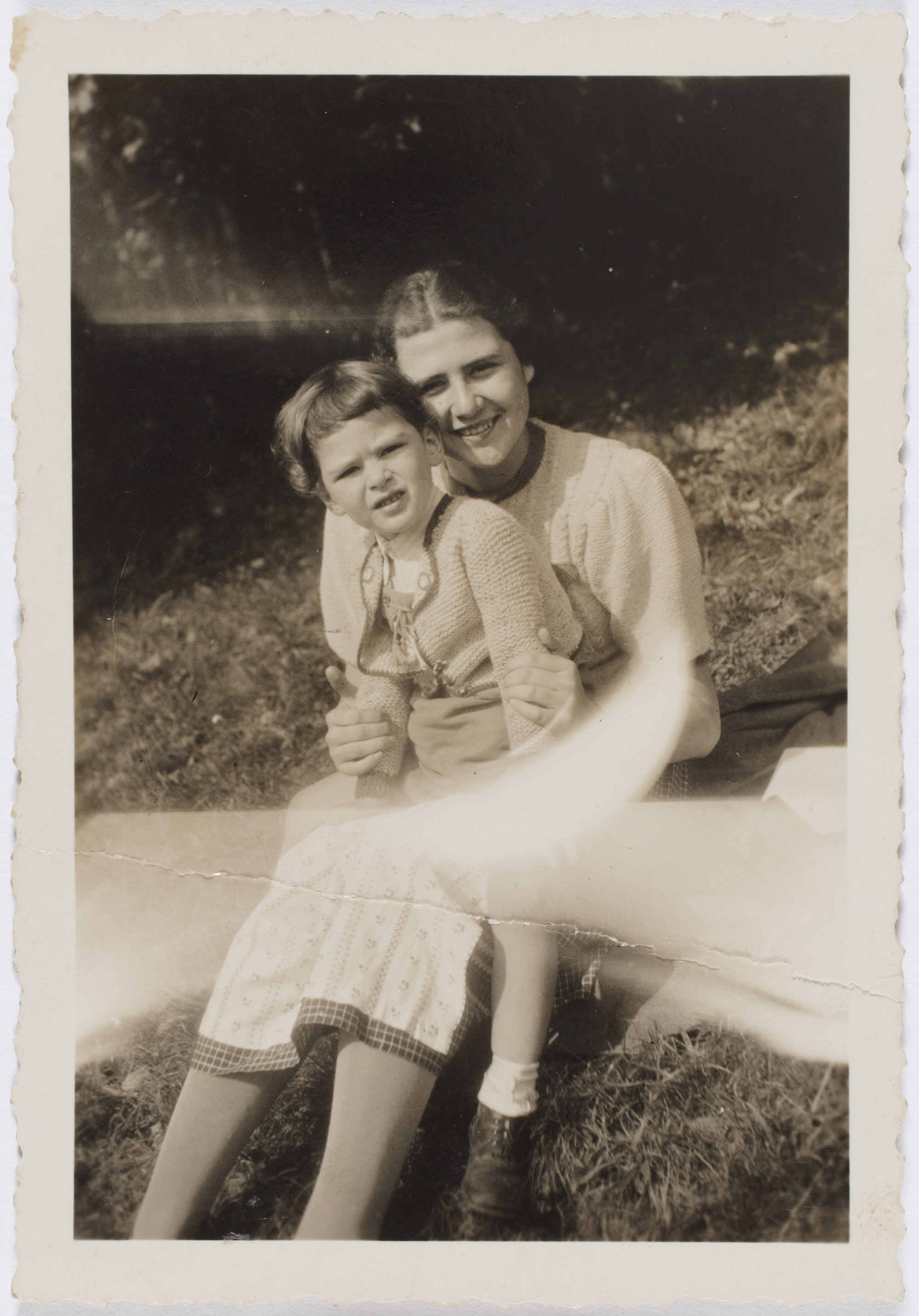 A faded B&W photograph of Edith Roll kneels with her brother fritz in her lap.
