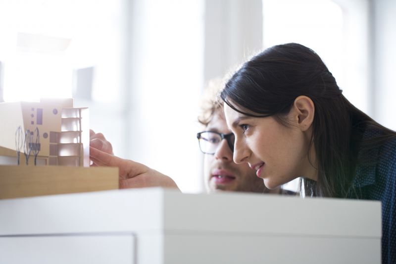 A male and female designers look at an architectural model